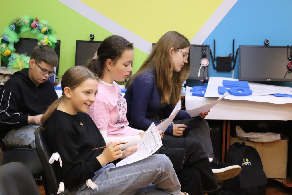 Підлітки сидять у бібліотеці, слухаючи гостю заходу